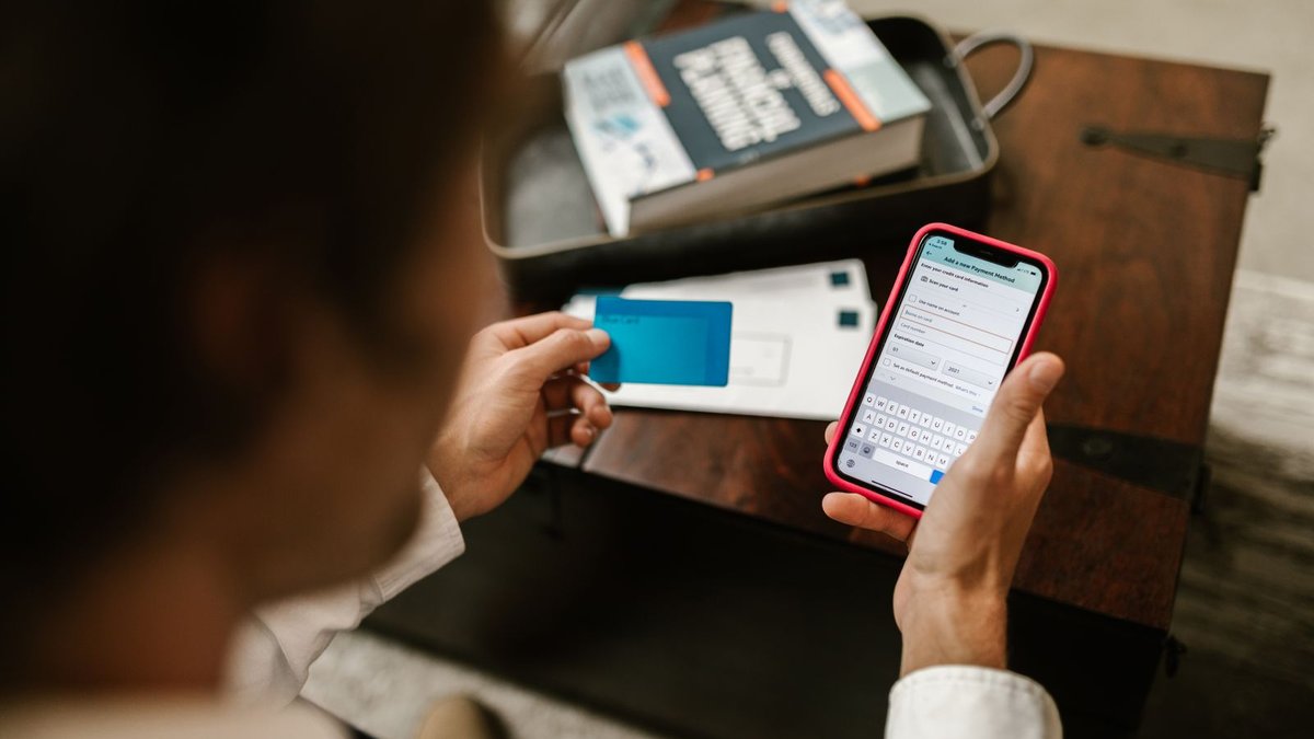 Pessoa segurando cartão e celular ao mesmo tempo, verificando informações