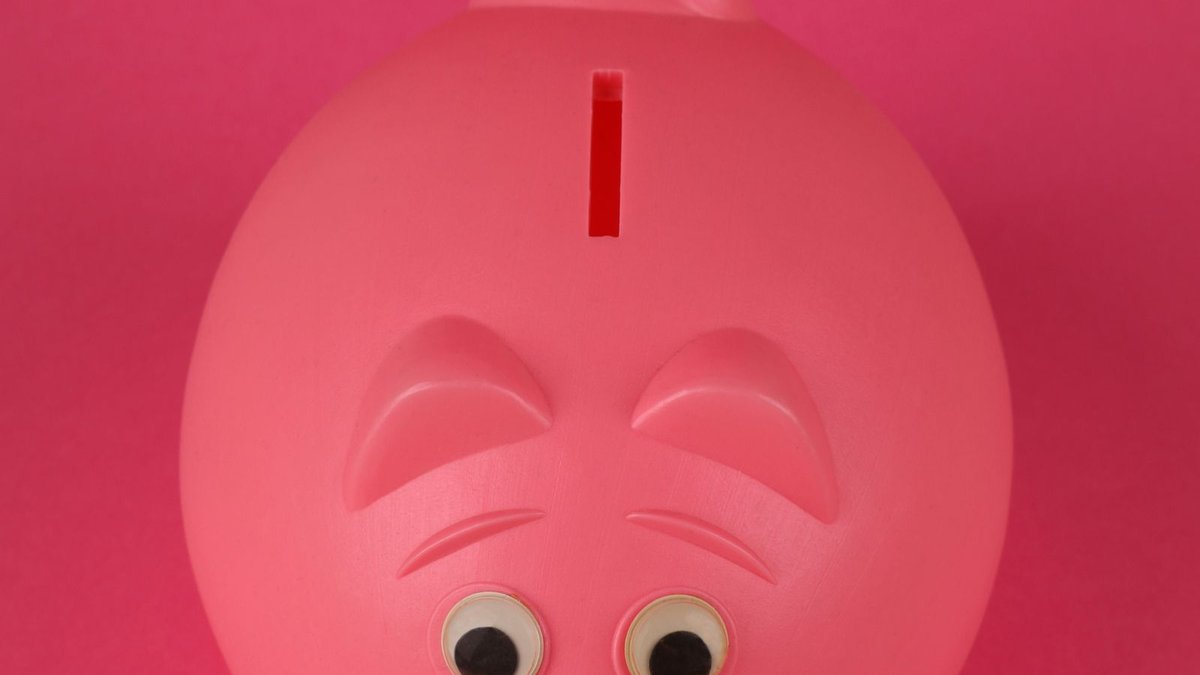 Cofrinho rosa em formato de porquinho sobre fundo colorido