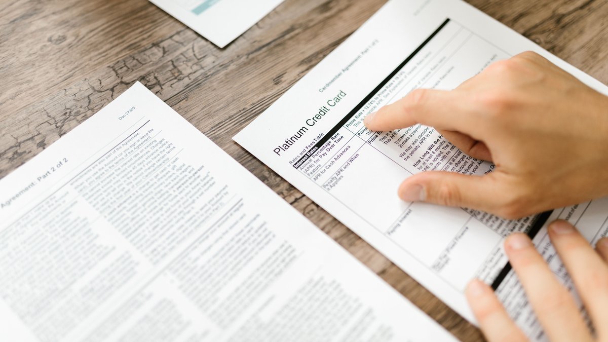 Pessoa lendo as letras miudas de um contrato financeiro
