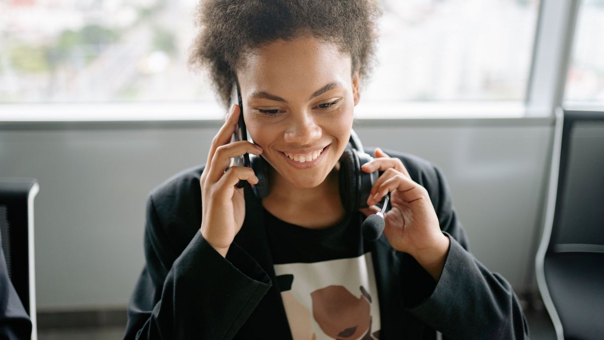 Mulher sorrindo enquanto fala ao telefone, representando atendimento ou negociação