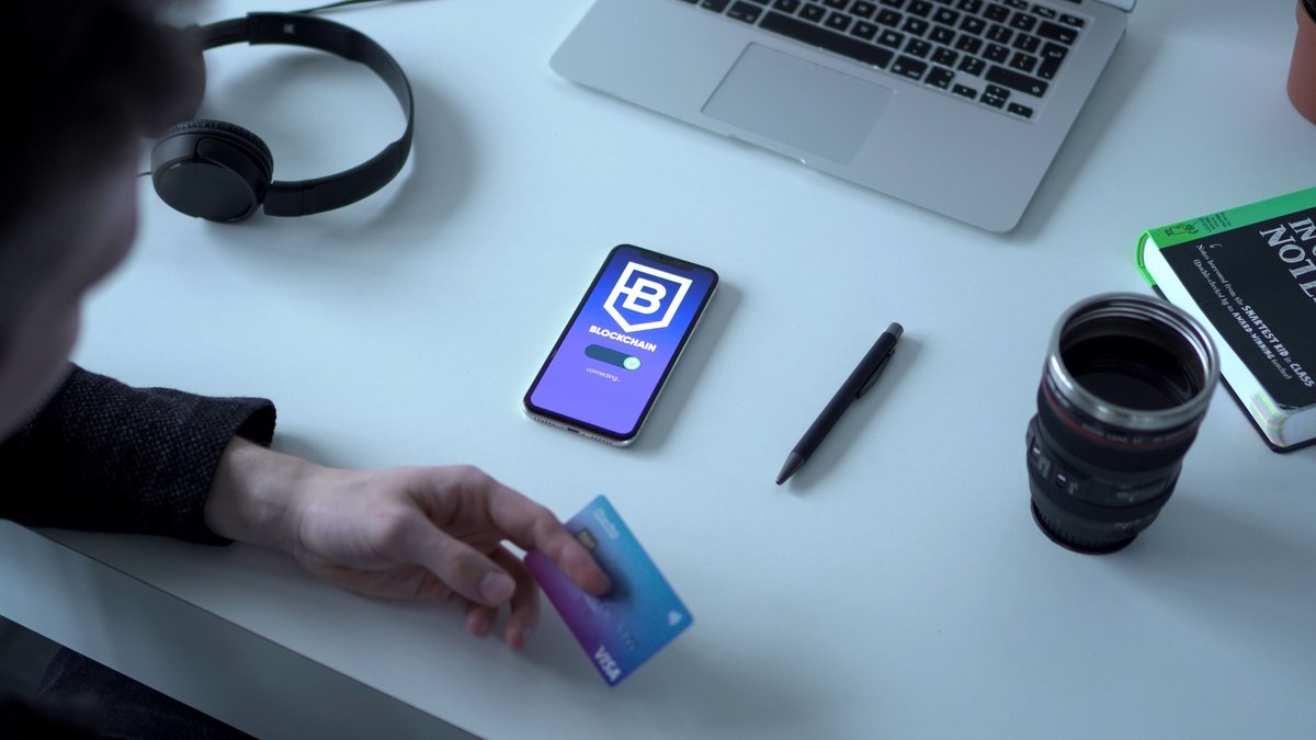 Pessoa segurando cartao e celular com aplicativo bancario aberto