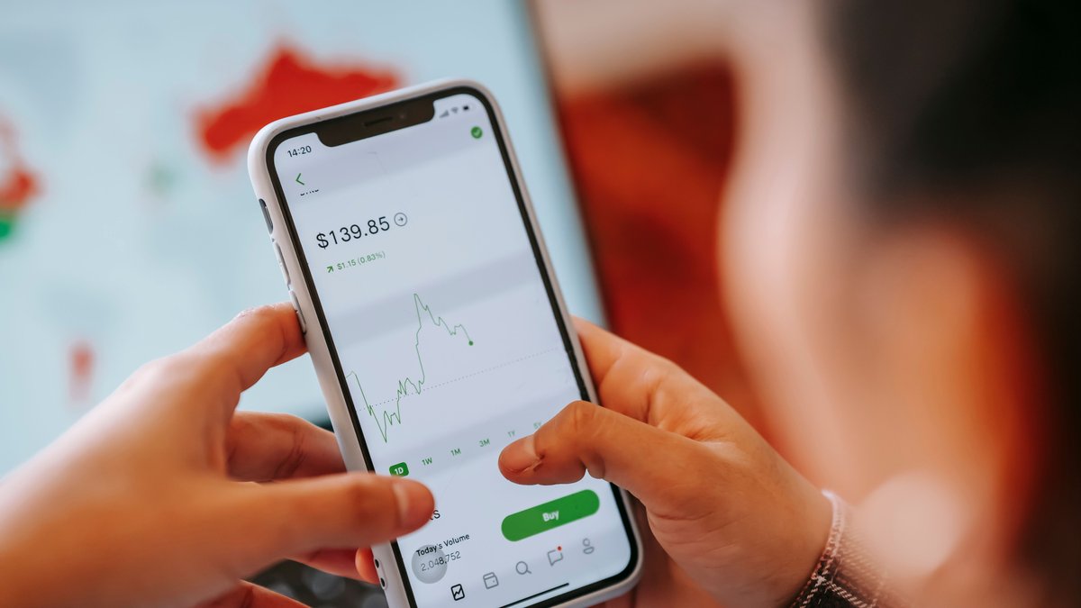 Pessoa comprando ativos pelo aplicativo de investimentos no celular
