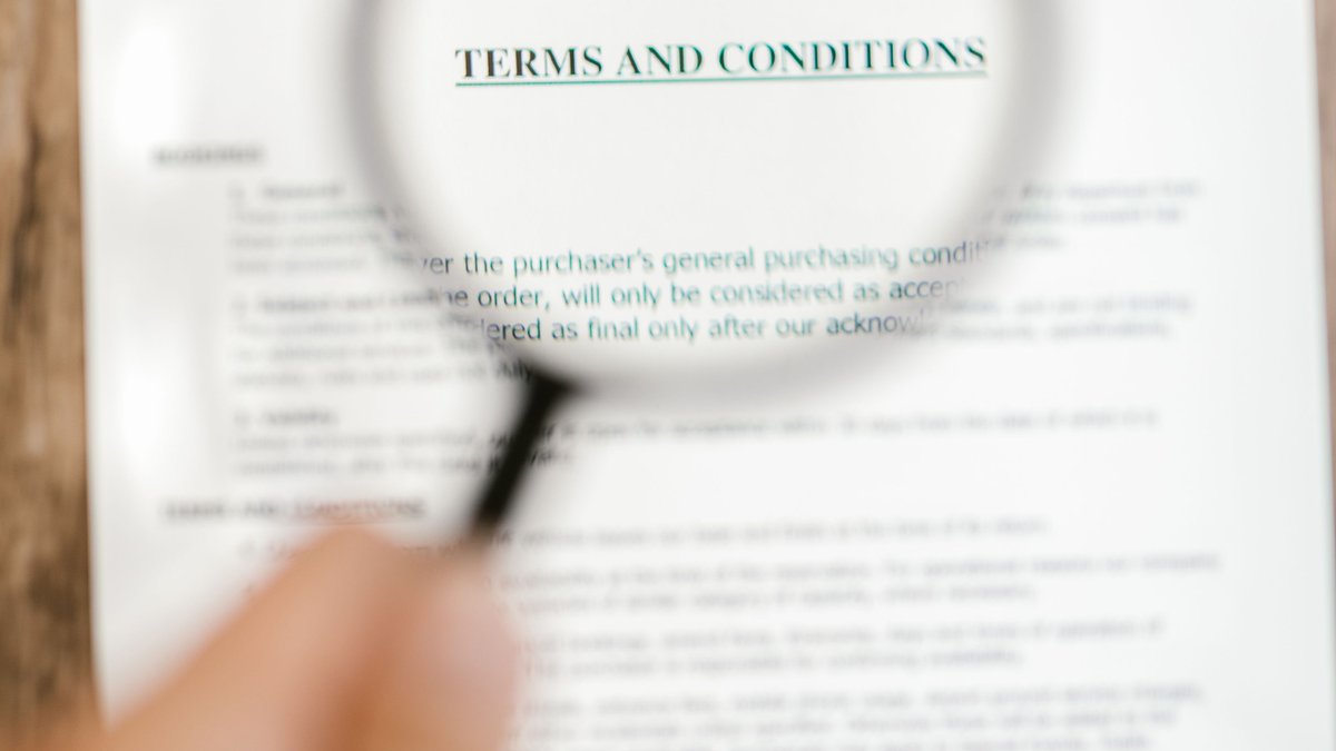 Lupa ampliando texto de termos e condicoes em um contrato