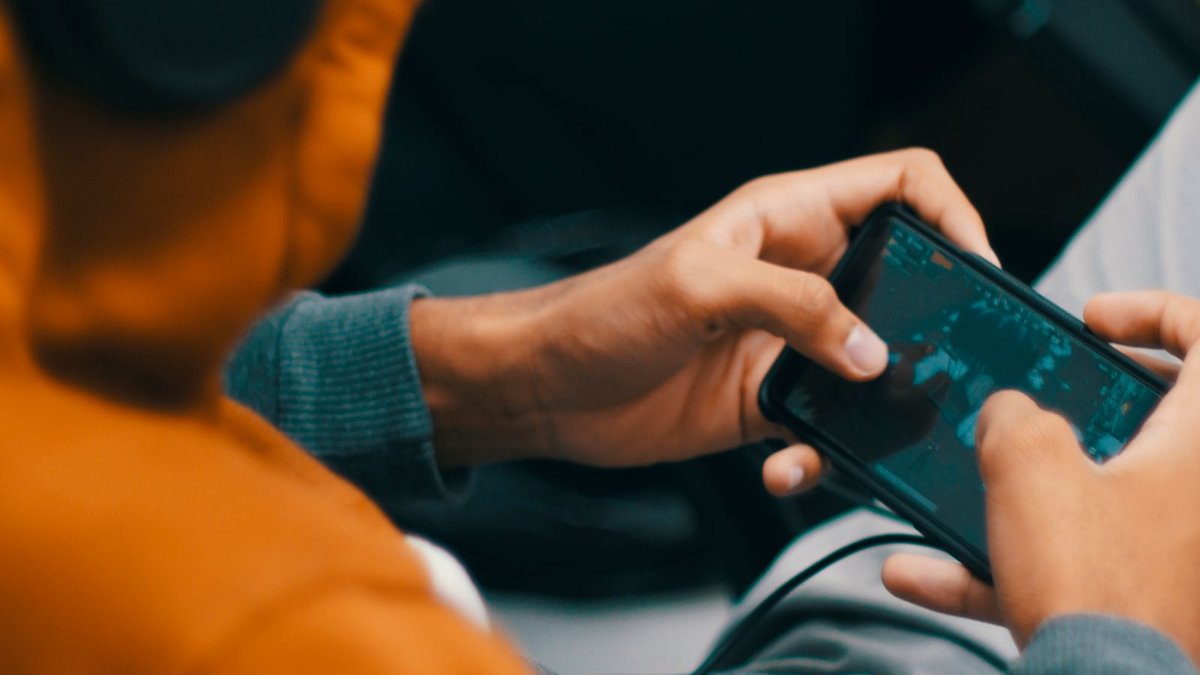 Pessoa jogando em um celular com tela escura