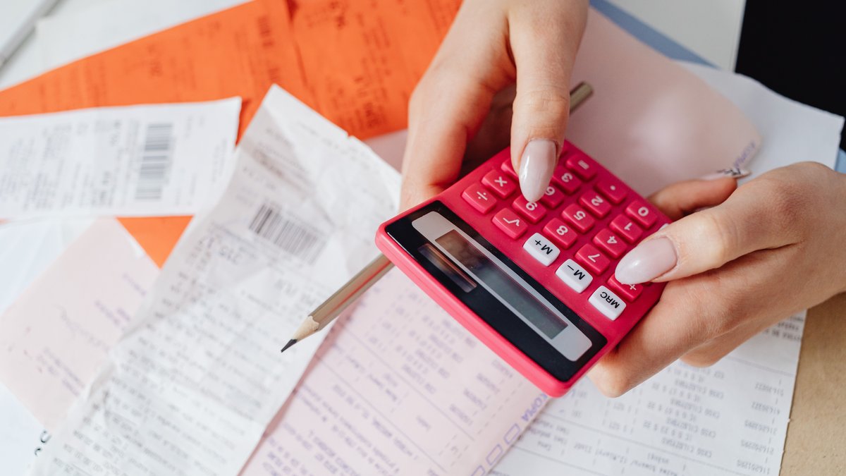 Pessoa calculando recibos e notas fiscais de um pequeno negocio