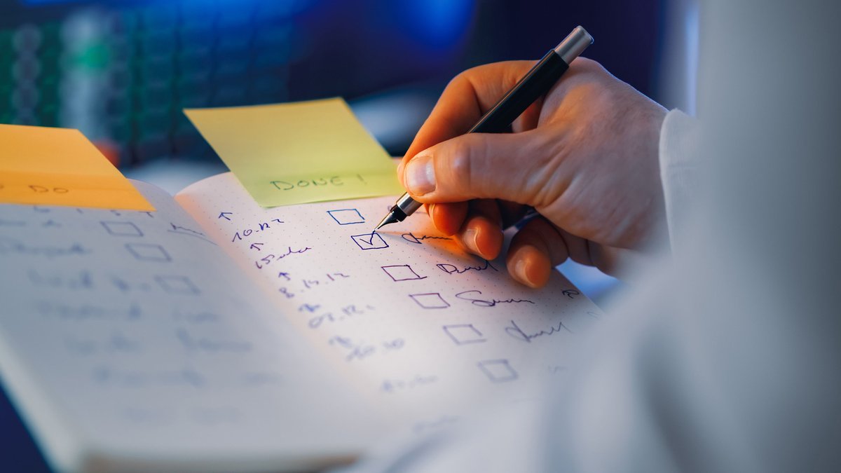 Mão marcando itens de uma checklist financeira no papel
