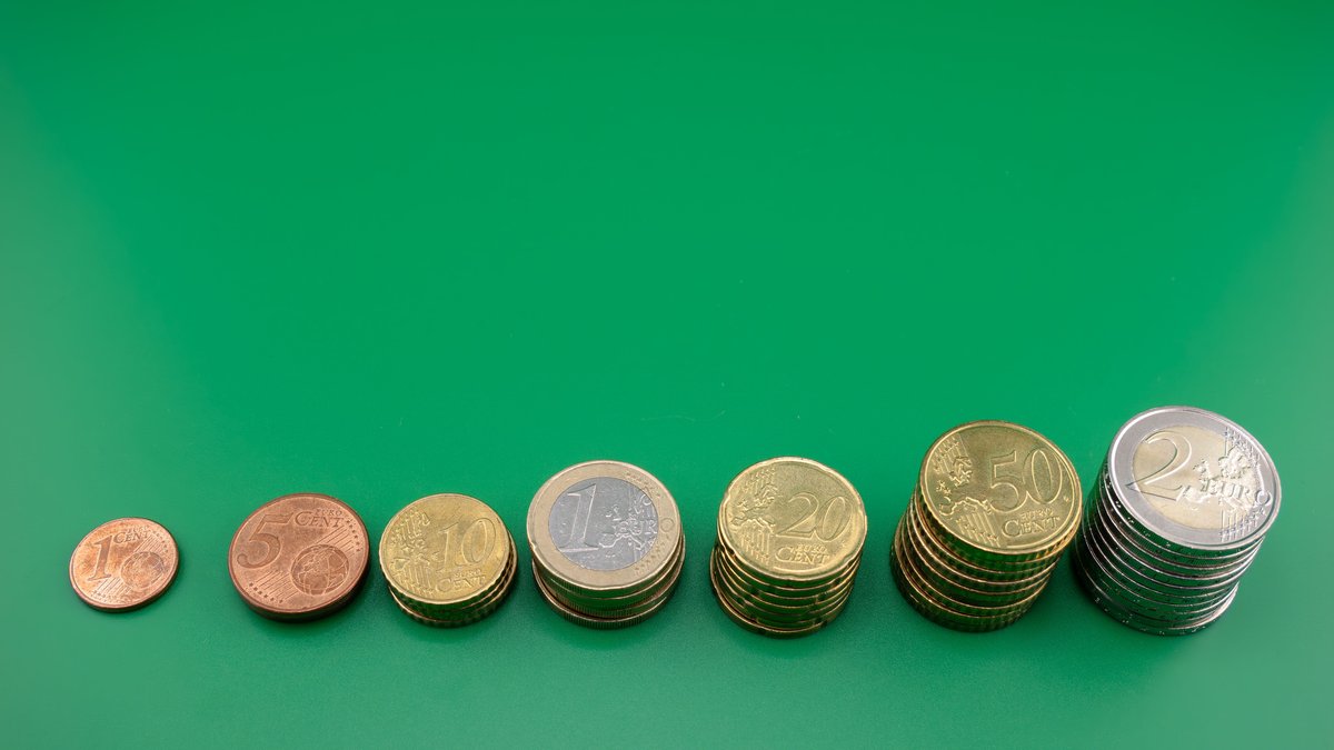 Moedas organizadas em ordem crescente sobre superficie verde