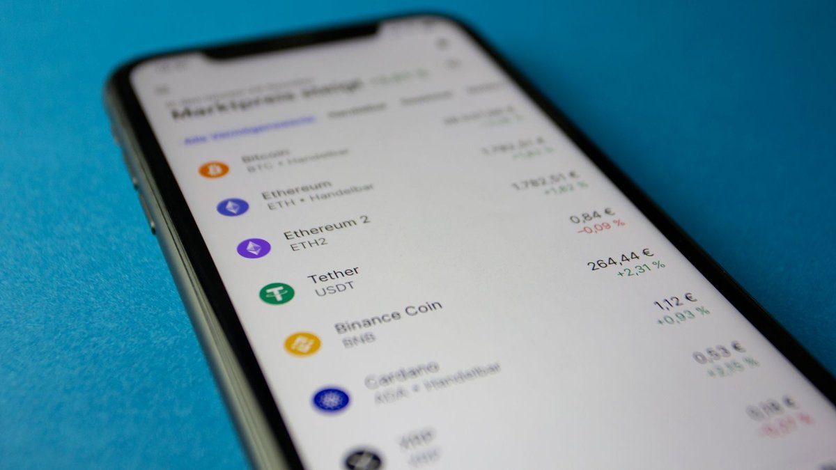 Celular exibindo lista de criptomoedas num aplicativo de carteira digital